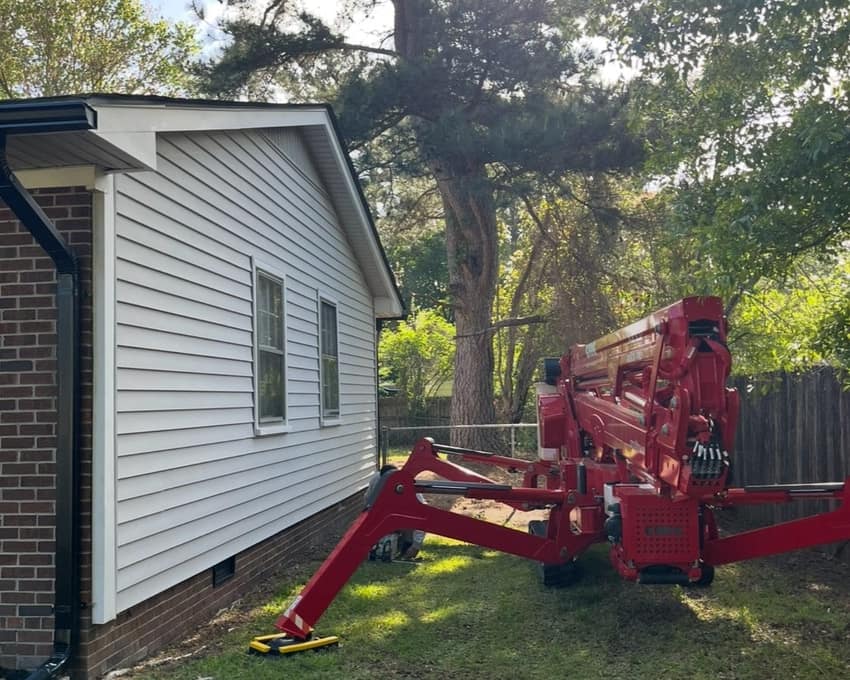 Spider lift positioned beside a house for a tight-access tree removal